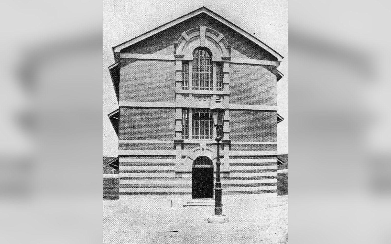 Old photograph of Boggo Road Gaol's brick facade with barred windows and a lone lamppost